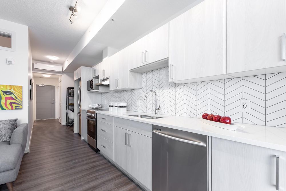 Galley kitchen with white cabinetry and stainless appliances